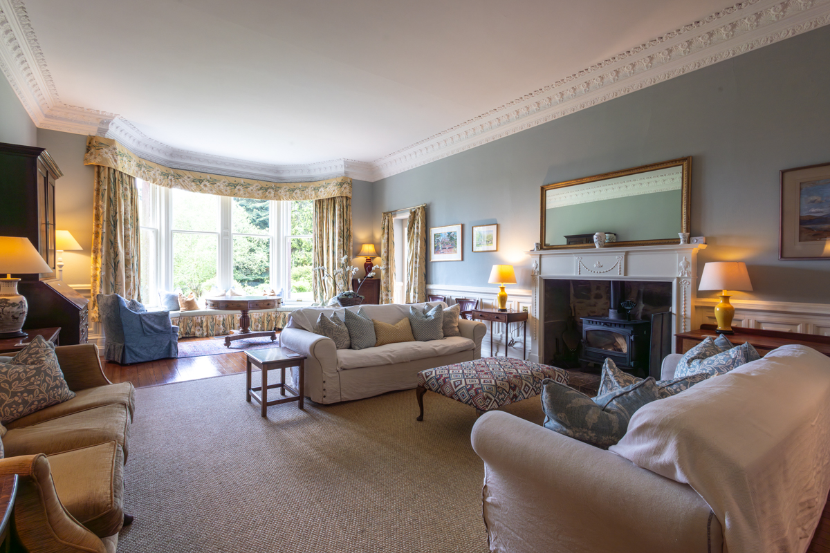 The drawing room with bay window, fireplace, and soft seating